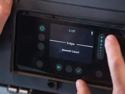 Ein Mitarbeiter einer Sanit&auml;r- und Heizungsbaufirma installiert eine moderne Gasbrennwerttherme in einem Einfamilienhaus.