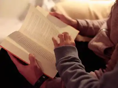 Eine Mutter liest ihrer kleinen Tochter aus einem Buch vor.