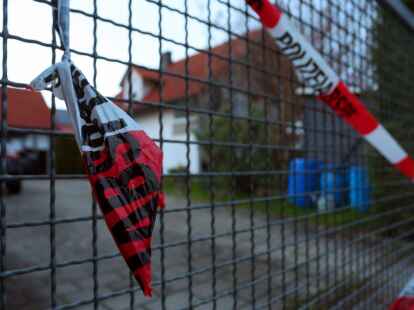Ein Absperrband der Polizei h&auml;ngt am Hoftor des Einfamilienhauses, in dem die Leichen eines Ehepaars entdeckt wurden.