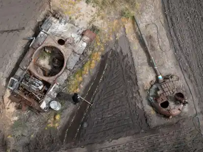 Ein Mann pflanzt in der Region Kiew Sonnenblumen in seinem Garten neben einem besch&auml;digten russischen Panzer und einem Panzerturm.