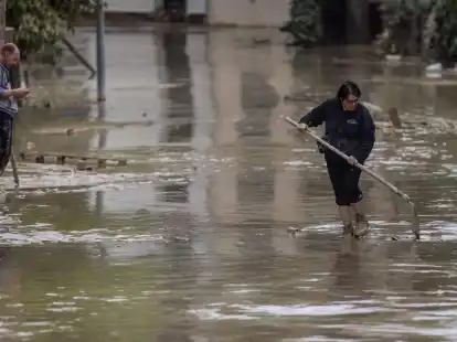 Anwohner versuchen nach &Uuml;berschwemmungen eine Stra&szlig;e in Faenza von Schlamm und Wasser zu befreien.