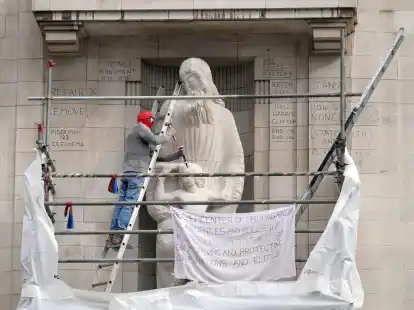 Ein Mann mit einer Spiderman-Maske besch&auml;digt die Statue eines umstrittenen Bildhauers am Hauptquartier der BBC in London.