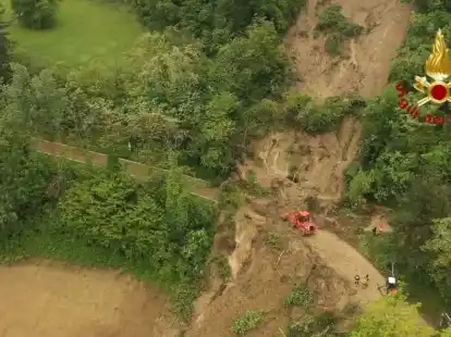 Mit schwerem Ger&auml;t befreit die Feuerwehr nach einem Erdrutsch einen Stra&szlig;enabschnitt in Norditalien von Schlamm (Aufnahme mit einer Drohne).