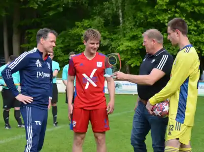 Ehrung nach dem Spiel: Der Bezirks-Spielausschussvorsitzende Stefan Brinker überreicht die Meistertrophäe an VfL-Kapitän Silas Dohrmann.