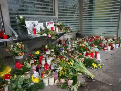 Kerzen und Blumen stehen und liegen im Bahnhof Brokstedt in einem Warteh&auml;uschen.