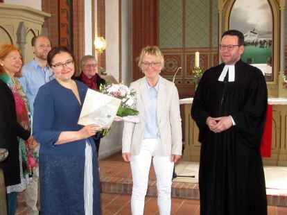 Inselpastor Christian Neumann und der Kirchenvorstand &uuml;berreichen Olga Persits die Urkunde am Ende des Pfingstgottesdiensts.