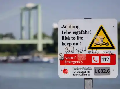 Ein Schild am Rheinufer weist auf die Gefahren beim Schwimmen im Fluss hin.
