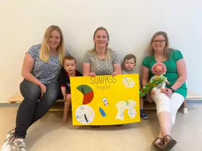 Liesa Rickmann (links) von der Kita Schatzkiste, Charleen Melzer (Mitte) von der Kita Muschelbank und Sarah Duske, Einrichtungsleiterin der Kita Sandburg, pr&auml;sentieren mit zwei Kindergartenkindern das Projekt &bdquo;Sun-Pass&ldquo;.