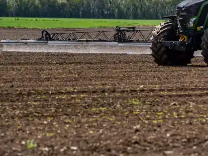 Ein Traktor bringt auf einem Acker Pflanzenschutzmittel aus.