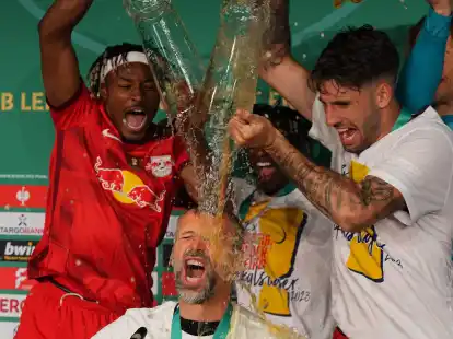 Leipzigs Spieler &uuml;bergie&szlig;en Trainer Marco Rose mit Bier w&auml;hrend der Pressekonferenz.