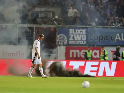 Bielefelds Fabian Klos l&auml;uft vor Rauchbomben auf dem Rasen.