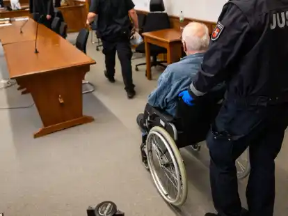 Der Angeklagte wird im Rollstuhl in den Saal des Landgerichts geschoben.