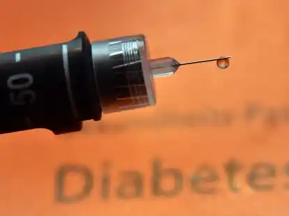 Ein Tropfen Insulin h&auml;ngt an der Nadel einer wiederverwendbaren Spritze, einem sogenannten Pen, f&uuml;r Diabetiker.