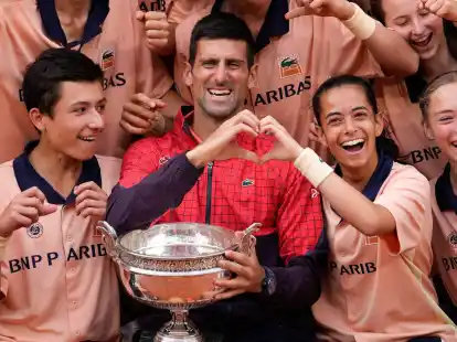 Nach seinem Sieg bei den French Open posiert Novak Djokovic (M.) mit Ballm&auml;dchen und Balljungen.