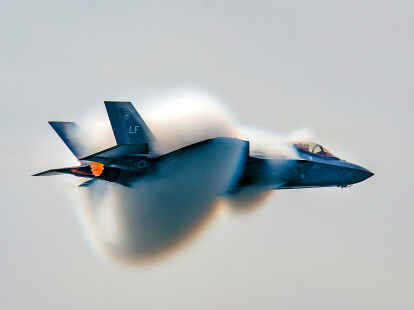 Ein F-35 vom Heritage Flight Team vollzieht einen Hochgeschwindigkeitsflug. Bei der &Uuml;berschreitung der Schallgeschwindigkeit ist die Wolke sehr gut zu erkennen.