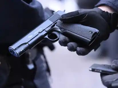 Ein Polizist h&auml;lt eine Softair-Pistole in die Kamera (Symbolbild)