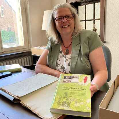 Das Ergebnis von 19 Jahren Arbeit: Hilke Hinrichs h&auml;lt ihre Fikensolter Chronik in den H&auml;nden. Auf dem Schreibtisch liegen Dokumente aus dem 17. Jahrhundert, mit denen sie viele Stunden verbracht hat.