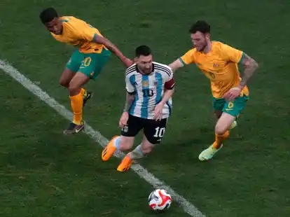 Lionel Messi (M) setzt sich im&nbsp;Dribbling gegen zwei Gegenspieler durch.