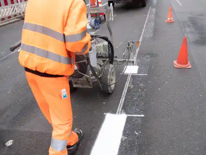 Arbeiter bei Markierungsarbeiten auf einer Stra&szlig;e.