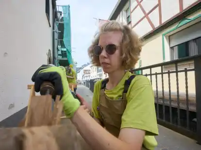 Die freiwillige Helferin Julie bearbeitet den Balken eines Fachwerkhauses.