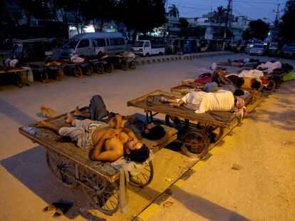 Verk&auml;ufer und Rikscha-Fahrer schlafen an einem hei&szlig;en Sommermorgen in Karachi im Freien.