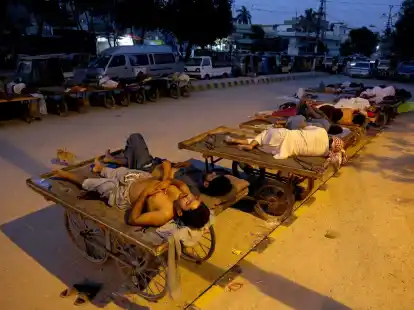 Verk&auml;ufer und Rikscha-Fahrer schlafen an einem hei&szlig;en Sommermorgen in Karachi im Freien.