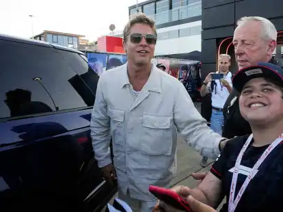 Schauspieler Brad Pitt l&auml;chelt den Fans zu, die das Fahrerlager verlassen.