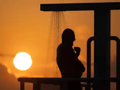 Ein Mann erfrischt sich unter einer Dusche.