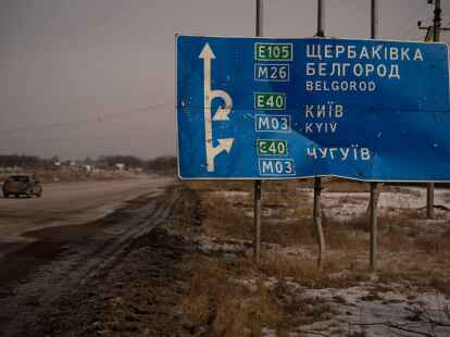 Ein Auto f&auml;hrt an einem von Kugeln und Granatsplittern besch&auml;digten Stra&szlig;enschild auf der Stra&szlig;e zur russischen Stadt Belgorod vorbei.