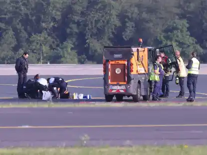 Sicherheitspersonal und Polizisten versuchen am D&uuml;sseldofer Flughafen, Aktivisten vom Asphalt auf dem Rollfeld zu l&ouml;sen.