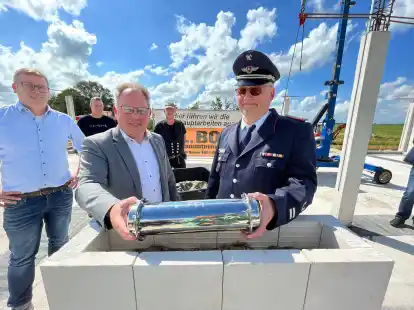 Samtgemeindeb&uuml;rgermeister Harald Hinrichs (l.) und Ortsbrandmeister Stefan Bender legen eine Zeitkapsel in die Mauern des neuen Hauses.