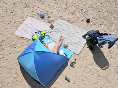 Eine Frau genie&szlig;t in ihrer Sonnenmuschel das Sommerwetter am Badesee.