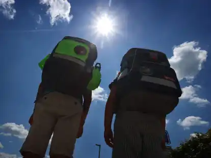 Zwei Kinder laufen mit ihren Schulranzen im Sonnenschein.