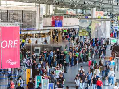 Reisende stehen am Frankfurter Flughafen beim Einchecken in einer langen Schlange.