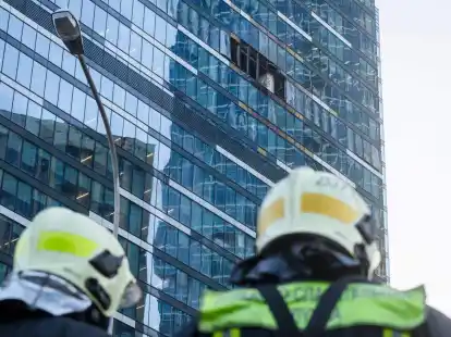 Feuerwehrleute stehen neben dem besch&auml;digten Hochhaus im Gesch&auml;ftsviertel Moskwa City.