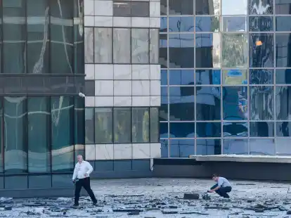 Ermittler inspizieren Tr&uuml;mmerteile unterhalb der besch&auml;digten Fassade eines Hochhauses in Moskaus B&uuml;roviertel Moskwa City. Das Geb&auml;ude wurde zum zweiten Mal von einer Drohne getroffen.