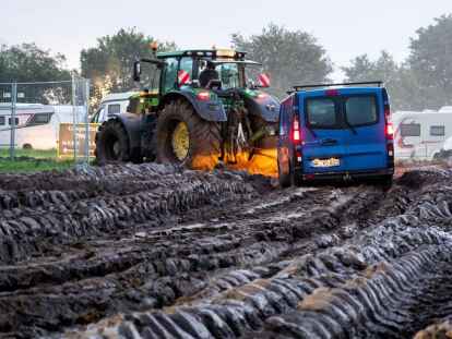 Autos werden mit Hilfe eines Traktors auf das Gelände des Heavy-Metal-Festivals in Wacken durch den Schlamm gezogen.