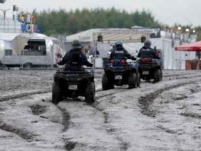 Polizisten auf motorisierten Quads sind auf dem  schlammigen Festivalgelände unterwegs.