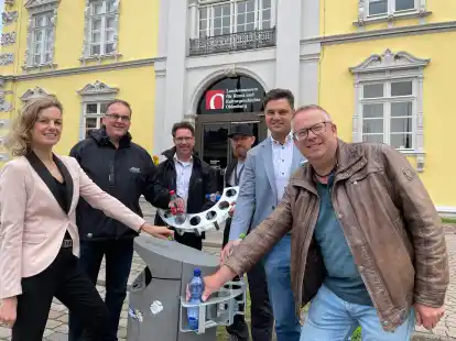 Passt genau (von links):  Julia Figura, Torsten von Varel (Abteilungsleiter Stra&szlig;enreinigung und Werkstatt des AWB), AWB-Betriebsleiter Volker Schneider-K&uuml;hn, Michael G&ouml;tze (Vertretung Schlosserei), Philip Bangen (Gesch&auml;ftsf&uuml;hrer zentegra) und Thomas Bruns (Werkstattleitung) bef&uuml;llen einen der &bdquo;Oldenburger Pfandretter&ldquo; am Schlossplatz.