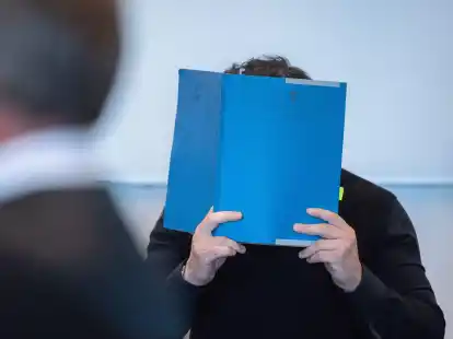 Einer der Hauptangeklagten versteckt zu Beginn des Prozess wegen Betrugs mit Corona-Tests sein Gesicht.