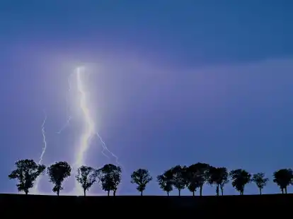 Ein Blitz eines Gewitters erhellt den Nachthimmel &uuml;ber der Landschaft im Osten des Landes Brandenburg.