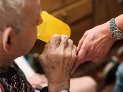 Eine ambulante Pflegerin hilft einem alten Mann bei der Tabletteneinnahme.