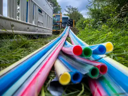 Leerrohre f&uuml;r das sp&auml;tere Verlegen von Glasfaserkabeln f&uuml;r den Breitband-Internetausbau liegen vor einer Horizontalbohrmaschine neben einer Kreisstra&szlig;e. Witterungsbedingungen erschweren im Kreis Aurich immer wieder den Ausbau - zuletzt der viele Regen.