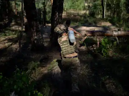 Ein ukrainischer Soldat tr&auml;gt eine Granate in Richtung einer Haubitze an der Frontlinie bei Lyman.