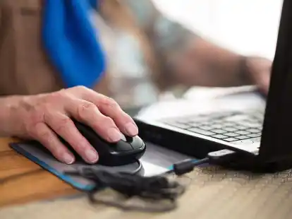 Eine Seniorin sitzt an ihrem Laptop.