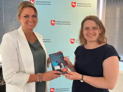 Austausch im Ministerium: Schulleiterin Silke M&uuml;ller (li.) &uuml;berreicht ihr Buch &bdquo;Wir verlieren unsere Kinder&ldquo; an Kultusministerin Julia Willie Hamburg