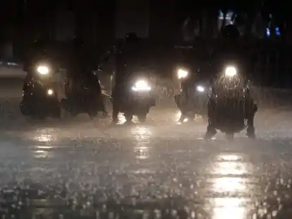 Rollerfahrer stehen bei heftigem Regen an einer Kreuzung in Taipeh.