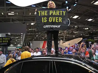 Eine Greenpeace-Aktivistin bei der Er&ouml;ffnung der IAA auf dem Dach eines ausgestellten Autos.
