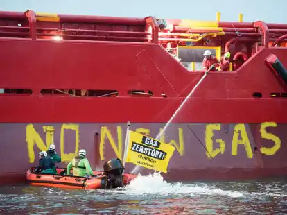 Greenpeace-Aktivisten mit einem Schlauchboot vor einem Schiff im Hafen von Mukran.