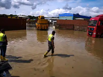 Arbeiter laufen nach &Uuml;berschwemmungen durch schwere Regenf&auml;lle durch das Hochwasser.